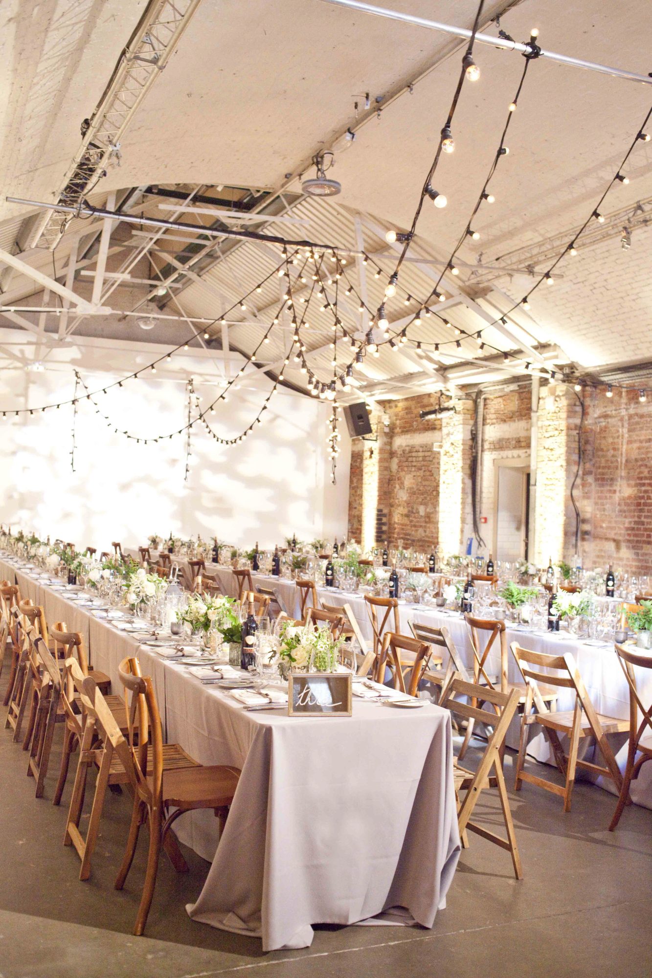 Long tables under festoon lights at a London warehouse wedding